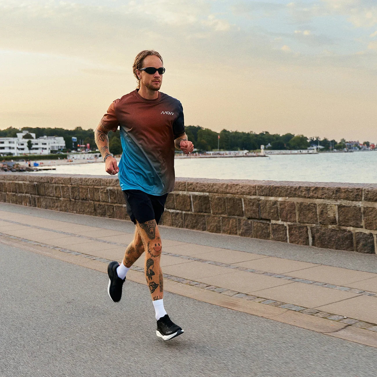 Man running on waterfront path wearing injury reduction white and grey minimalist running shoes